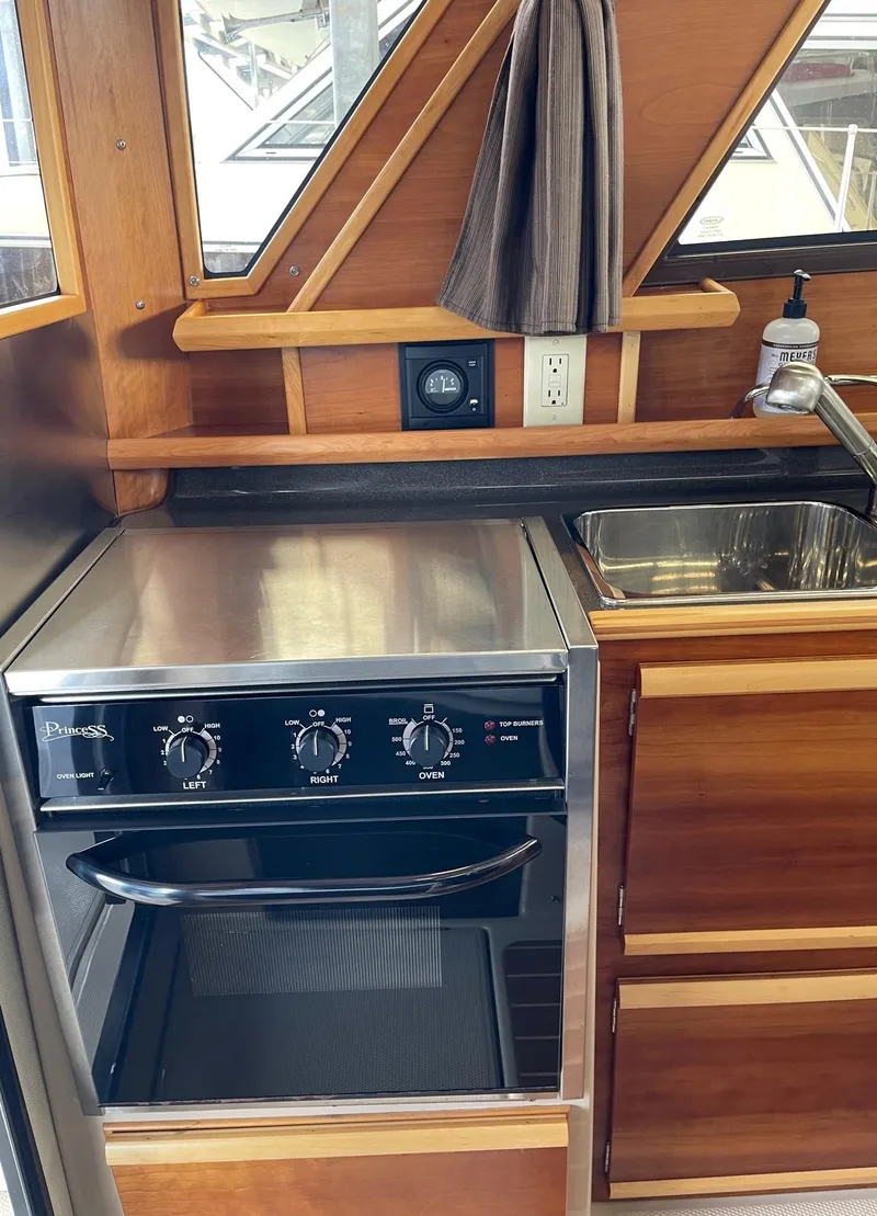 Slide: The Image of 2015 Cutwater C-28 boat kitchen with stove and sink, featuring wood cabinetry. - 6