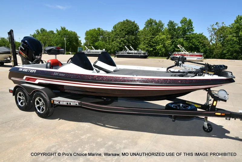 Slide: The Image of 2013 Skeeter ZX200 boat on trailer, parked outdoors, with trees in the background. - 79