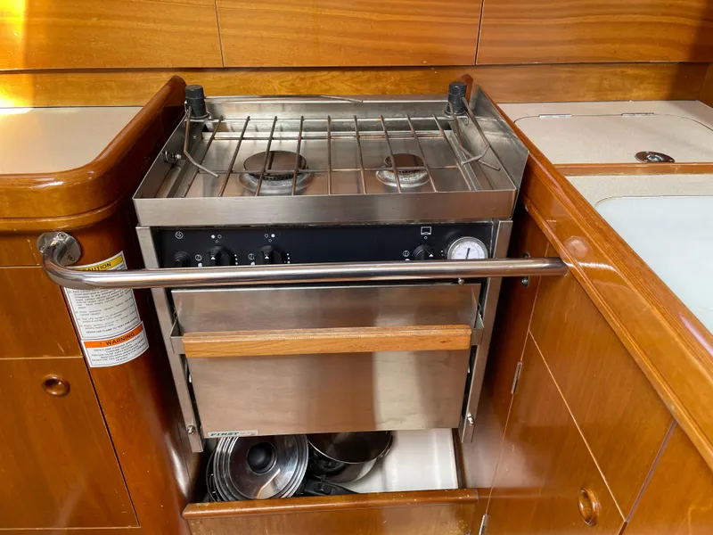Slide: The Image of Galley stove in 2000 Beneteau Oceanis 321 sailboat, featuring wood cabinetry and stainless steel finish. - 11