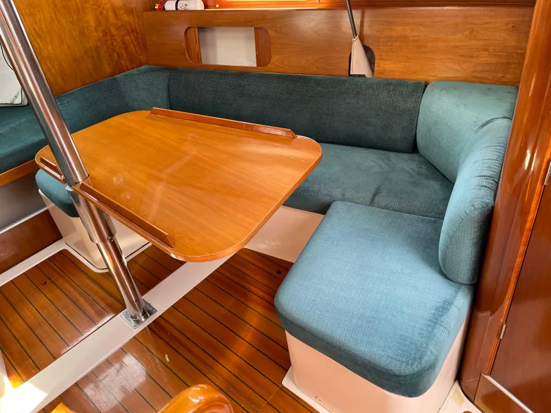 Slide: The Image of Interior of 2000 Beneteau Oceanis 321 sailboat with wooden table and blue seating. - 17