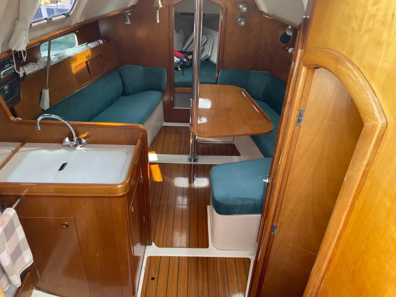 Slide: The Image of Interior of 2000 Beneteau Oceanis 321 sailboat with wood finish and teal seating. - 5