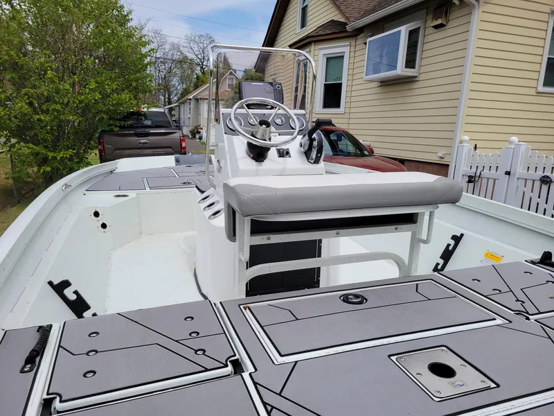 Slide: The Image of 2019 Crestliner 1800 Bay boat with center console and seating, parked near a house. - 2