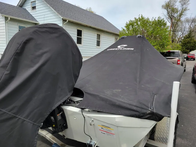 Slide: The Image of 2019 Crestliner 1800 Bay boat covered, parked near a house. - 4