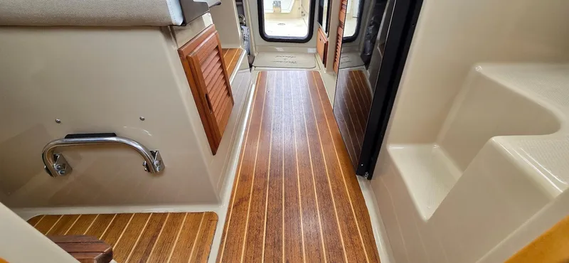 Slide: The Image of Interior of a 2013 Cutwater C-28 boat, featuring wood flooring and compact design. - 16