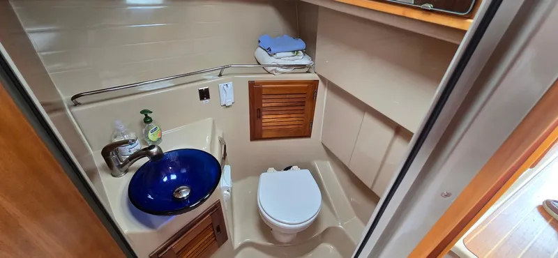 Slide: The Image of 2013 Cutwater C-28 boat bathroom with blue sink, toilet, and wooden cabinets. - 22
