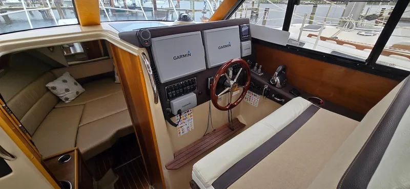 Slide: The Image of 2013 Cutwater C-28 boat interior with Garmin navigation, wooden steering wheel, and cozy seating area. - 26