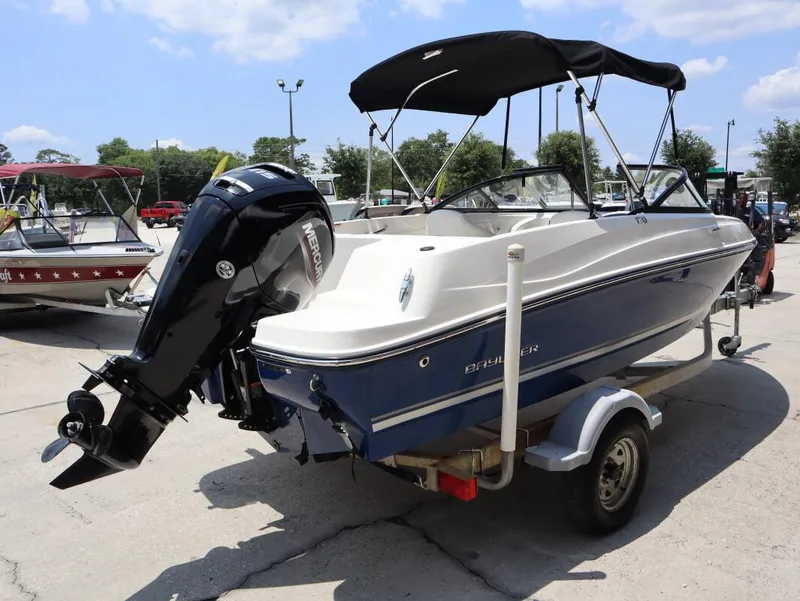 Slide: The Image of 2022 Bayliner 170 BR boat with Mercury outboard motor on trailer, parked outdoors. - 4
