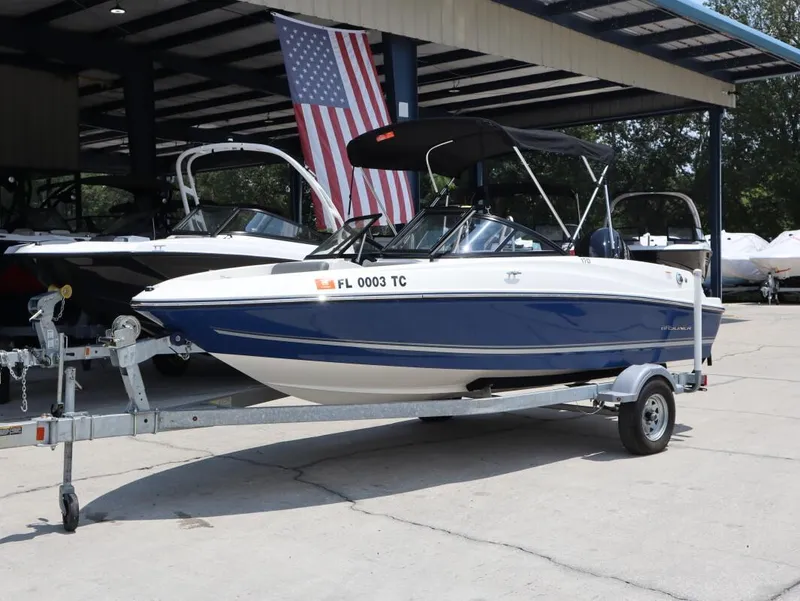 Slide: The Image of 2022 Bayliner 170 BR boat on trailer, parked under a canopy with American flag. - 7