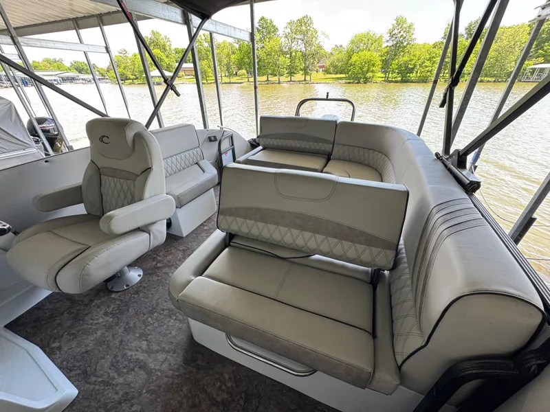 Slide: The Image of 2019 Crest Savannah 250 SLS pontoon boat interior with plush seating and scenic river view. - 17