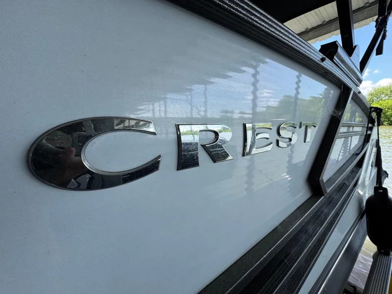 Slide: The Image of 2019 Crest Savannah 250 SLS boat with reflective logo, docked near water. - 7