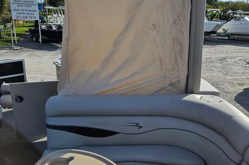 Slide: The Image of 2019 Bennington 20 SX pontoon boat with beige seating and canopy, parked outdoors. - 13
