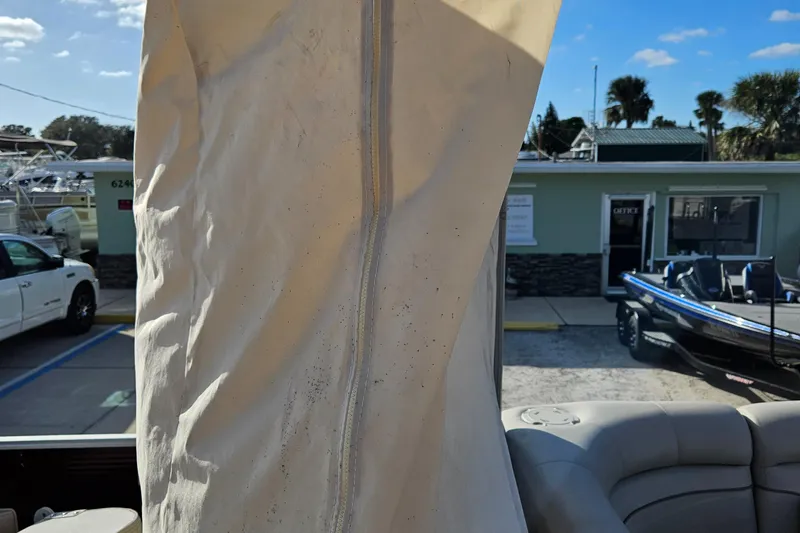 Slide: The Image of 2019 Bennington 20 SX boat with cover, parked near a building and other vehicles. - 16