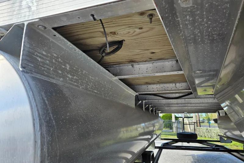 Slide: The Image of Underneath view of a 2019 Bennington 20 SX pontoon boat, showcasing aluminum structure and wiring. - 23