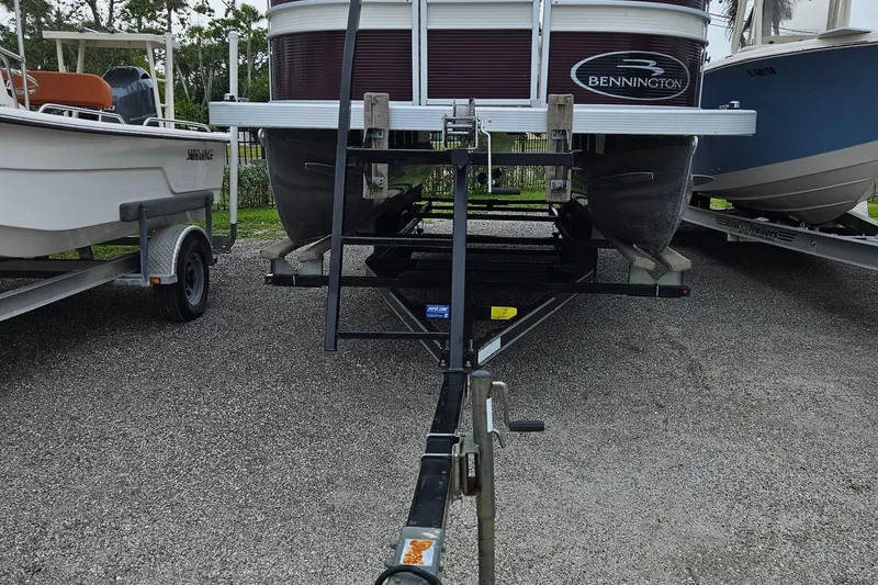 Slide: The Image of 2019 Bennington 20 SX pontoon boat on a trailer, parked on gravel. - 3