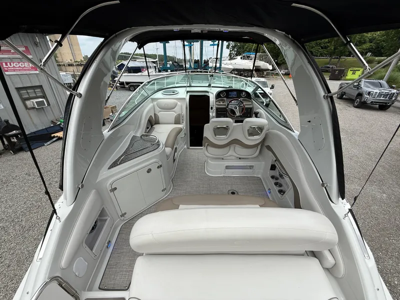 Slide: The Image of 2023 Crownline 270 CR boat interior with seating and helm, docked outdoors. - 7
