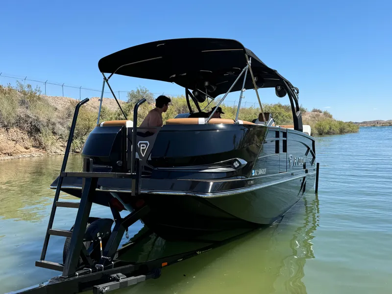 Slide: The Image of 2025 Paradigm 236 Surf SL boat on water, featuring sleek black design and canopy. - 10