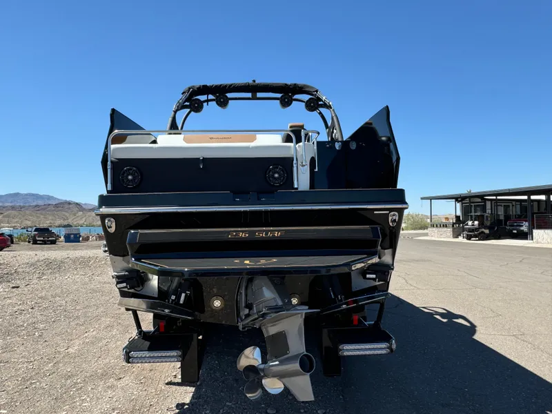 Slide: The Image of 2025 Paradigm 236 Surf SL boat, rear view, parked outdoors under clear blue sky. - 3