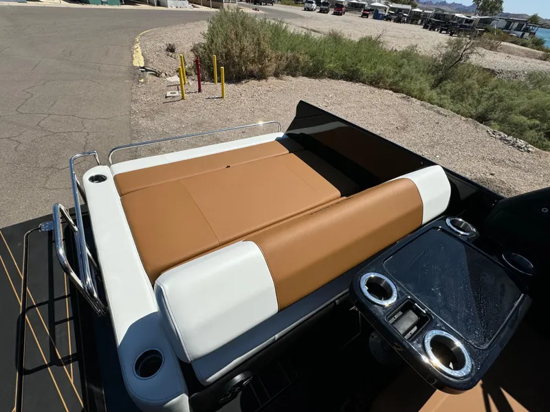 Slide: The Image of 2025 Paradigm 236 Surf SL boat with tan and white seating, cup holders, and scenic background. - 7