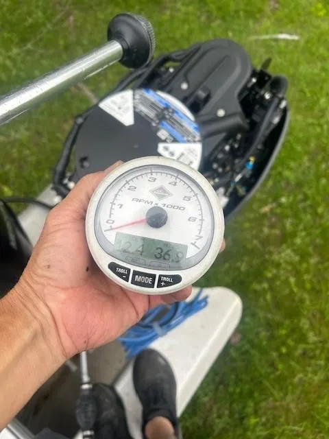 Slide: The Image of Hand holding a tachometer on a 2023 Sun Tracker Bass Buggy 16 XL Select boat. - 16