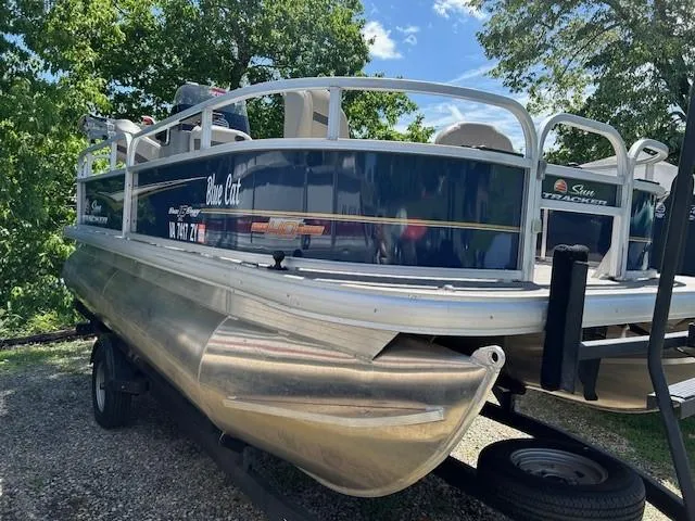 Slide: The Image of 2023 Sun Tracker Bass Buggy 16 XL Select pontoon boat on trailer, surrounded by trees. - 18