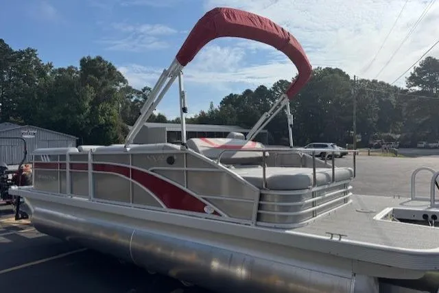 Slide: The Image of 2025 Bennington 22 SSXB pontoon boat with red canopy, parked outdoors. - 2