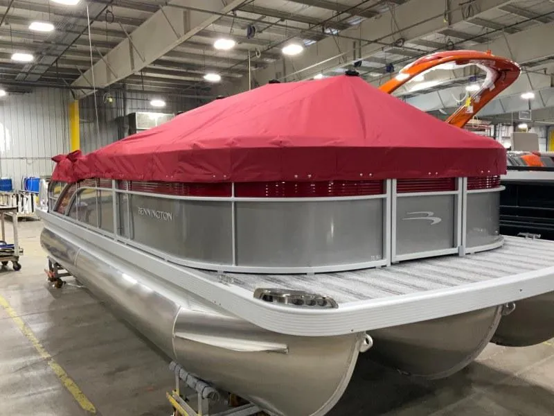 Slide: The Image of 2025 Bennington 22 SSXB pontoon boat with red cover in a warehouse setting. - 3