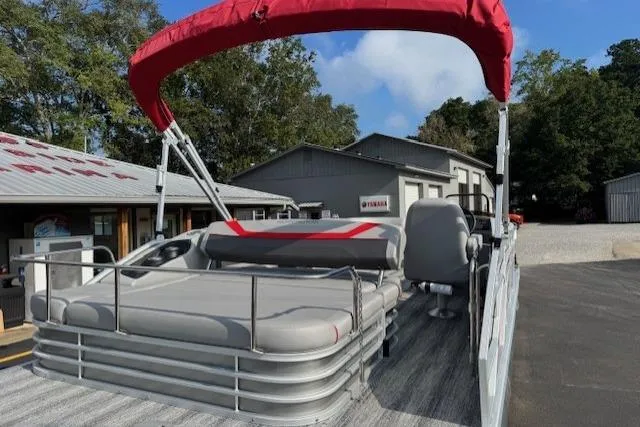 Slide: The Image of 2025 Bennington 22 SSXB pontoon boat with red canopy, parked outdoors. - 5