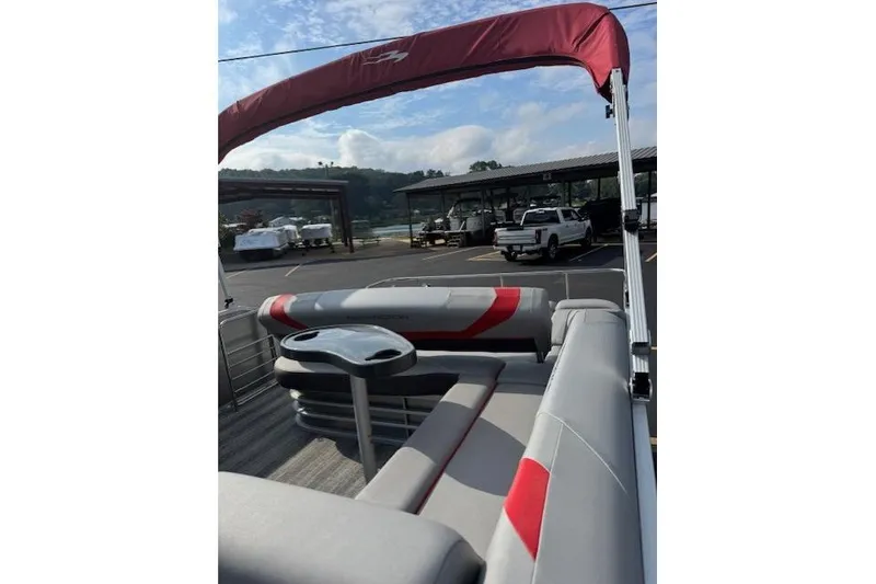 Slide: The Image of 2025 Bennington 22 SSXB pontoon boat with red canopy and seating, parked outdoors. - 7