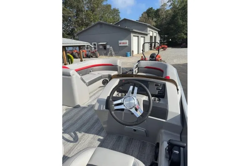 Slide: The Image of 2025 Bennington 22 SSXB boat interior with steering wheel and seating, parked outdoors. - 8