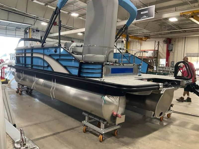 Slide: The Image of 2025 Bennington 22 LSB pontoon boat in a warehouse, showcasing sleek design and modern features. - 2