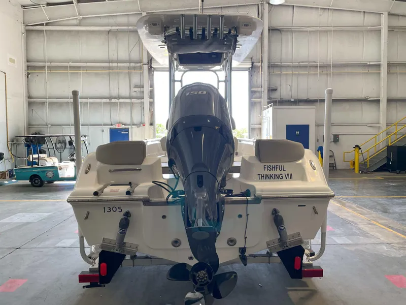 Slide: The Image of 2023 Key West 203 FS boat in a warehouse, rear view with outboard motor. - 2
