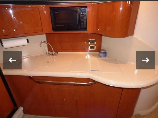 Slide: The Image of 1999 Sea Ray 380 Sundancer kitchen with wood cabinets, sink, and microwave. - 16