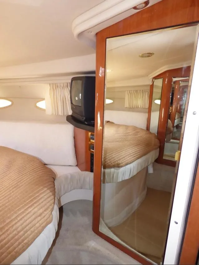 Slide: The Image of 1999 Sea Ray 380 Sundancer cabin with bed, TV, and mirrored closet. - 21