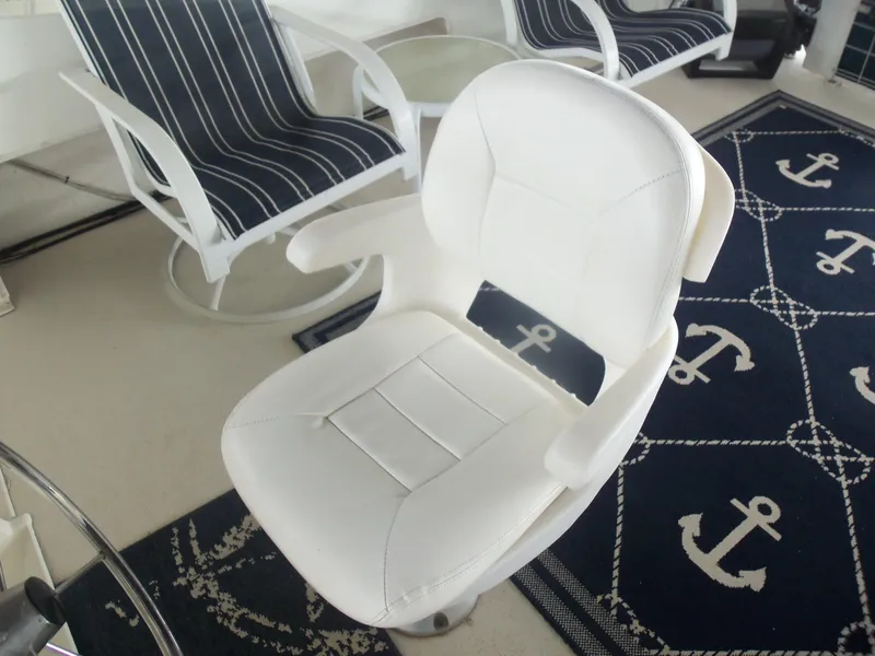 Slide: The Image of White boat chair on nautical-themed rug with anchor design, surrounded by striped seating. - 21