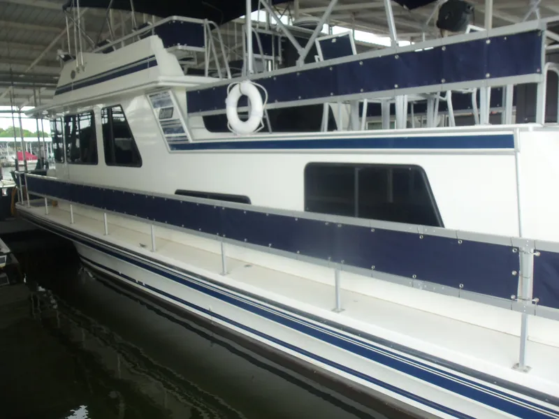 Slide: The Image of 2003 Gibson Classic houseboat with blue accents docked in a covered marina. - 3
