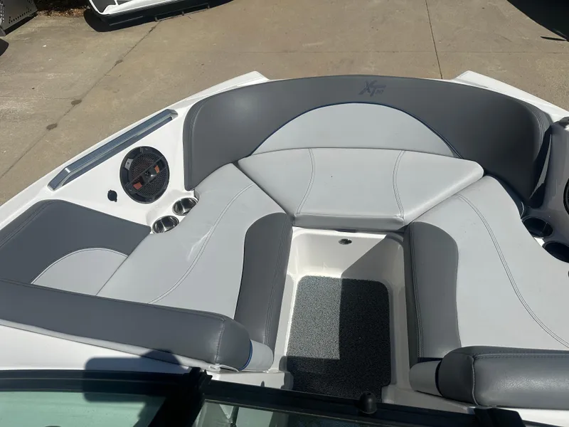 Slide: The Image of 2020 MasterCraft XT20 boat interior with gray and white seating, cup holders, and speaker. - 6