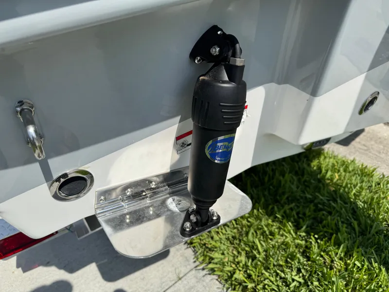 Slide: The Image of 2022 Sea Hunt Ultra 234 boat trim tab detail with actuator, on grass. - 15