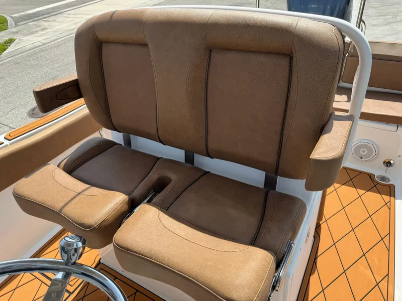 Slide: The Image of 2022 Sea Hunt Ultra 234 boat seating with brown cushions and steering wheel. - 40