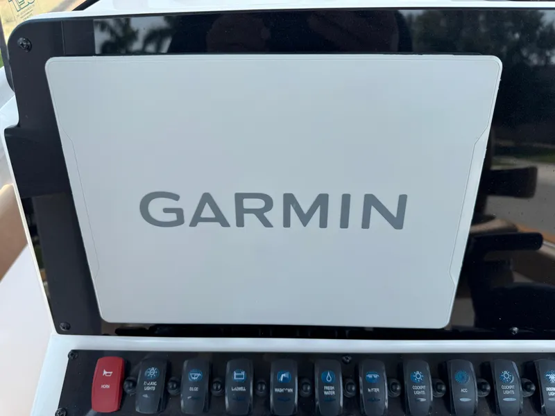 Slide: The Image of Garmin display on 2022 Sea Hunt Ultra 234 boat dashboard with control switches. - 46