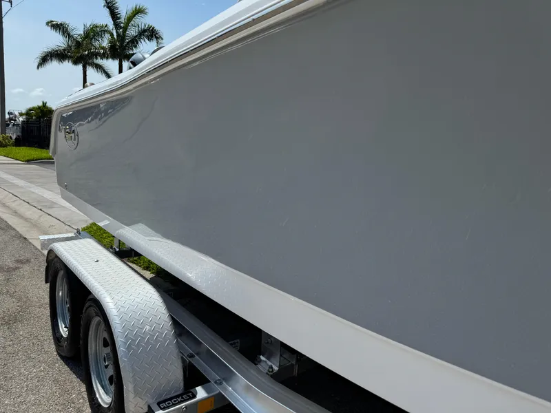 Slide: The Image of 2022 Sea Hunt Ultra 234 boat on trailer, palm trees in background. - 6