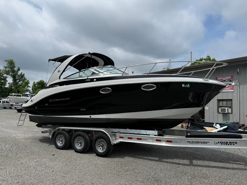 Slide: The Image of 2023 Crownline 264 CR boat on a trailer, parked outdoors. - 1