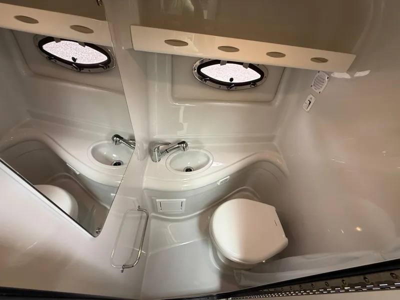 Slide: The Image of 2023 Crownline 264 CR boat bathroom with sink, toilet, and porthole window. - 22