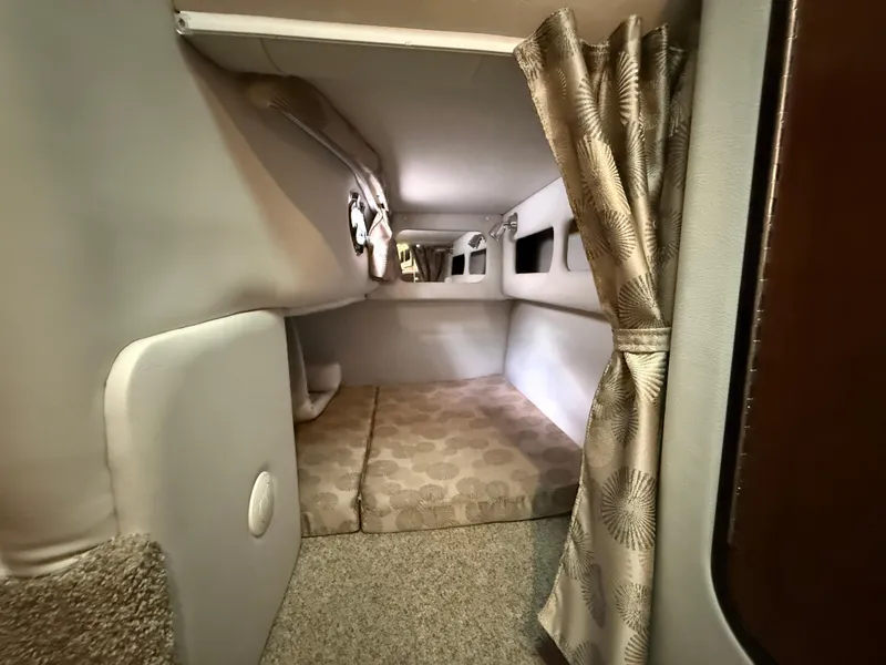 Slide: The Image of 2023 Crownline 264 CR cabin interior with cozy sleeping area and elegant curtains. - 24