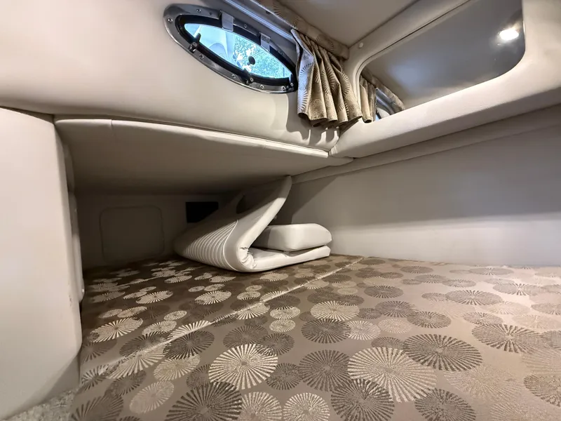 Slide: The Image of 2023 Crownline 264 CR cabin interior with patterned bedding and porthole window. - 25