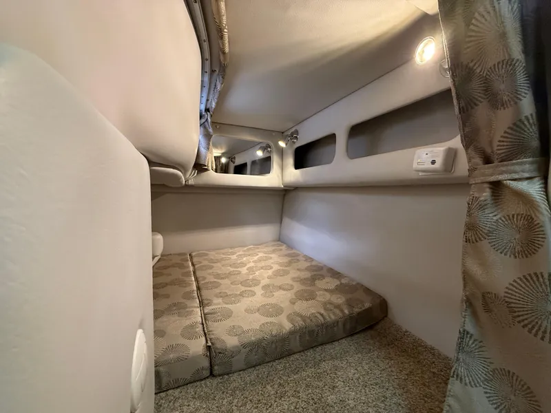 Slide: The Image of 2023 Crownline 264 CR cabin interior with cozy sleeping area and ambient lighting. - 26