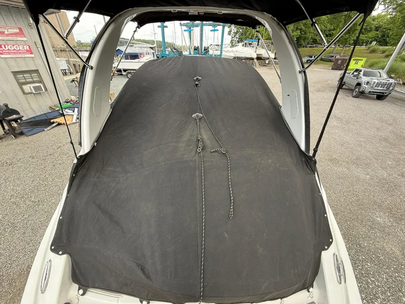 Slide: The Image of 2023 Crownline 264 CR boat with black cover in a marina setting. - 27