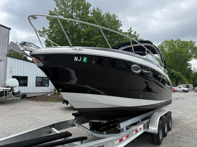 Slide: The Image of 2023 Crownline 264 CR boat on trailer, black hull, parked outdoors. - 3
