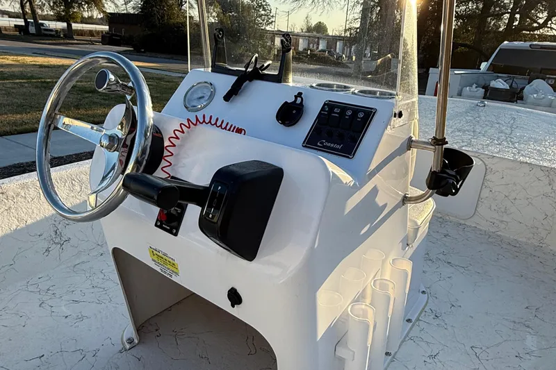 Slide: The Image of 2023 Coastal Skiff 171 boat console with steering wheel and controls in sunlight. - 5