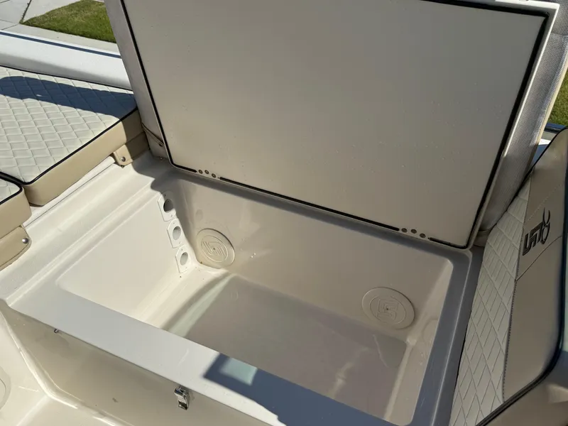 Slide: The Image of 2020 Carolina Skiff 21LS Dual Console boat storage compartment open, showcasing interior space. - 19