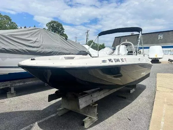 Slide: The Image of 2015 Bayliner Element E180 boat on display, parked outdoors under a partly cloudy sky. - 1